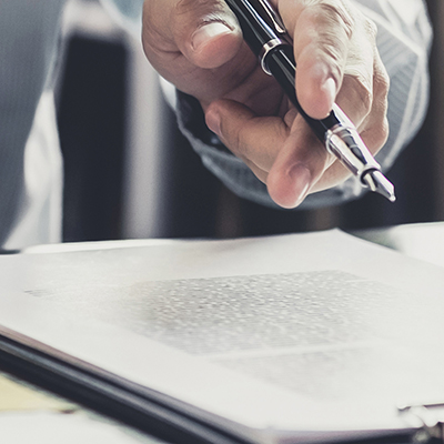 Image of a hand holding a pen over a document 
