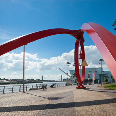 Image of the red steel Wave street sculpture on the banks of the river Usk 