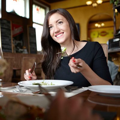 Woman eating pasta in restaurant